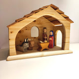 Krippe aus massivem Fichtenholz, veredelt mit Leinöl. Zeigt eine einfache Holzszene mit Maria, Josef und Jesuskind im Stall, begleitet von Esel und Ochse. Hergestellt in deutscher Holzmanufaktur.
