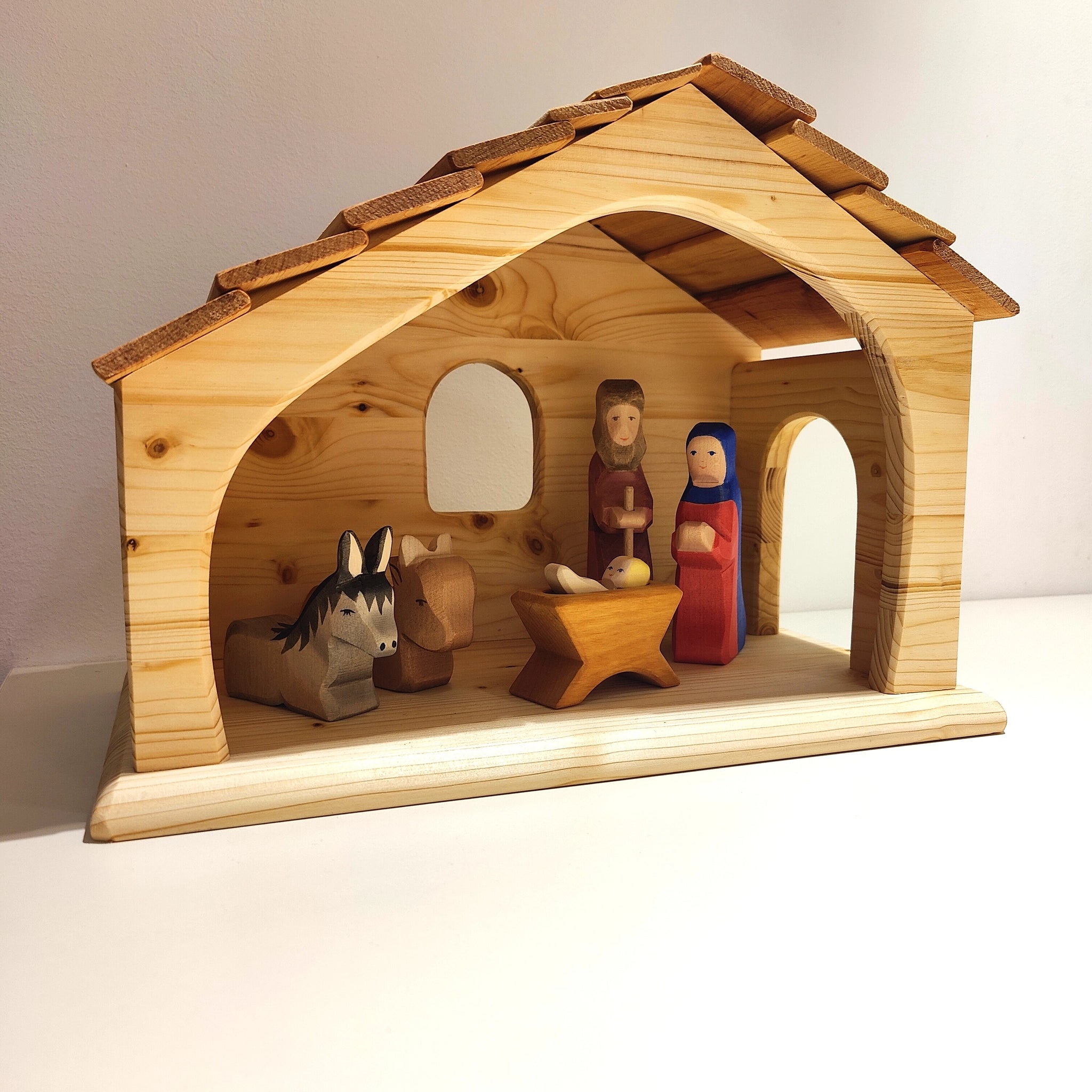 Krippe aus massivem Fichtenholz, veredelt mit Leinöl. Zeigt eine einfache Holzszene mit Maria, Josef und Jesuskind im Stall, begleitet von Esel und Ochse. Hergestellt in deutscher Holzmanufaktur.