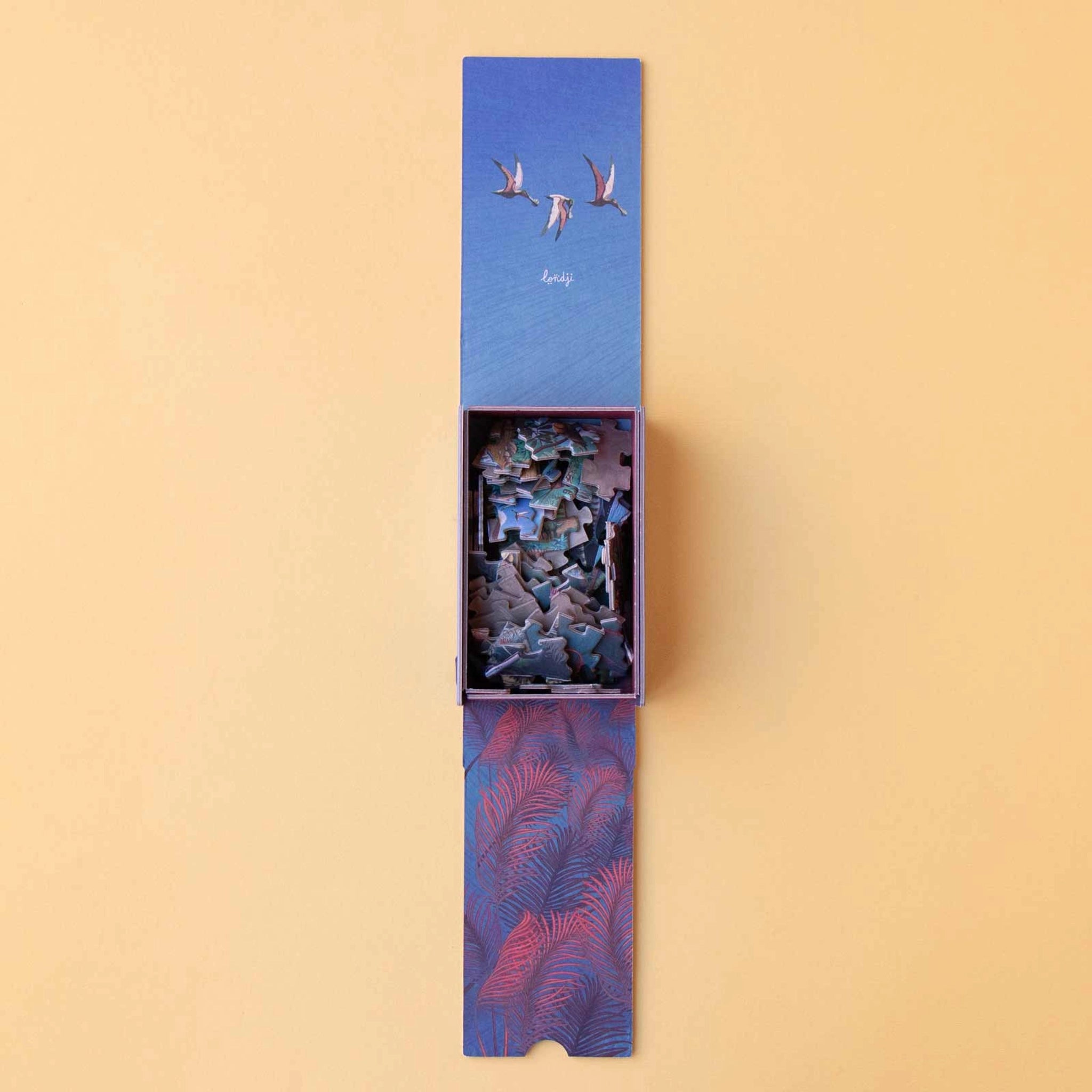 Minipuzzle: Dinosaurs in einer kleinen Londji-Schachtel mit offenem Schiebedeckel, zeigt Dinosaurier-Puzzleteile und Lernkarten. Nachhaltig aus FSC-Papier und recyceltem Karton hergestellt, ideal für Kinder ab 5 Jahren.