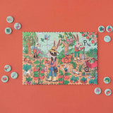 Minipuzzle: Garden zeigt drei anthropomorphe Hasen im Garten mit frischem Gemüse. Rund um das Puzzle liegen runde Spielsteine mit Gartensymbolen. Nachhaltig aus FSC-Papier und recyceltem Karton, ideal für Kinder ab 4 Jahren.