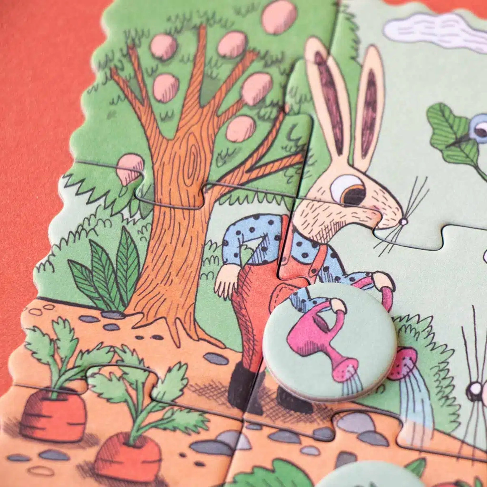 Minipuzzle: Garden zeigt einen Hasen in Latzhose, der mit einer rosa Gießkanne einen kleinen Garten mit Karotten und einem Obstbaum im Hintergrund gießt. Perfekt für Kinder ab 4 Jahren.