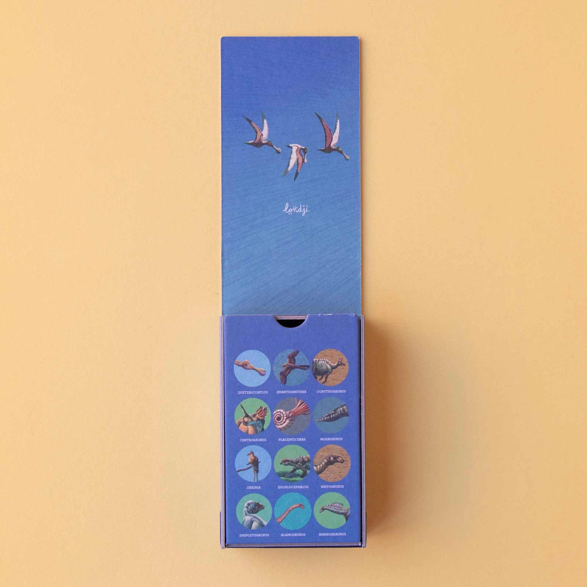 Minipuzzle: Dinosaurs, eine schlanke Schiebe-Box mit stilisiertem Logo und Pterosaurier-Illustration, enthält zwölf Karten mit prähistorischen Kreaturen, hergestellt aus FSC-Papier, ideal für unterwegs, für Kinder ab 5 Jahren.