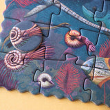 Minipuzzle: Dinosaurs zeigt ein nahes Bild eines Unterwasser-Puzzles mit ammonitenartigen Cephalopoden und roten Korallen auf FSC-Papier und recyceltem Karton, ideal für Kinder ab 5 Jahren.