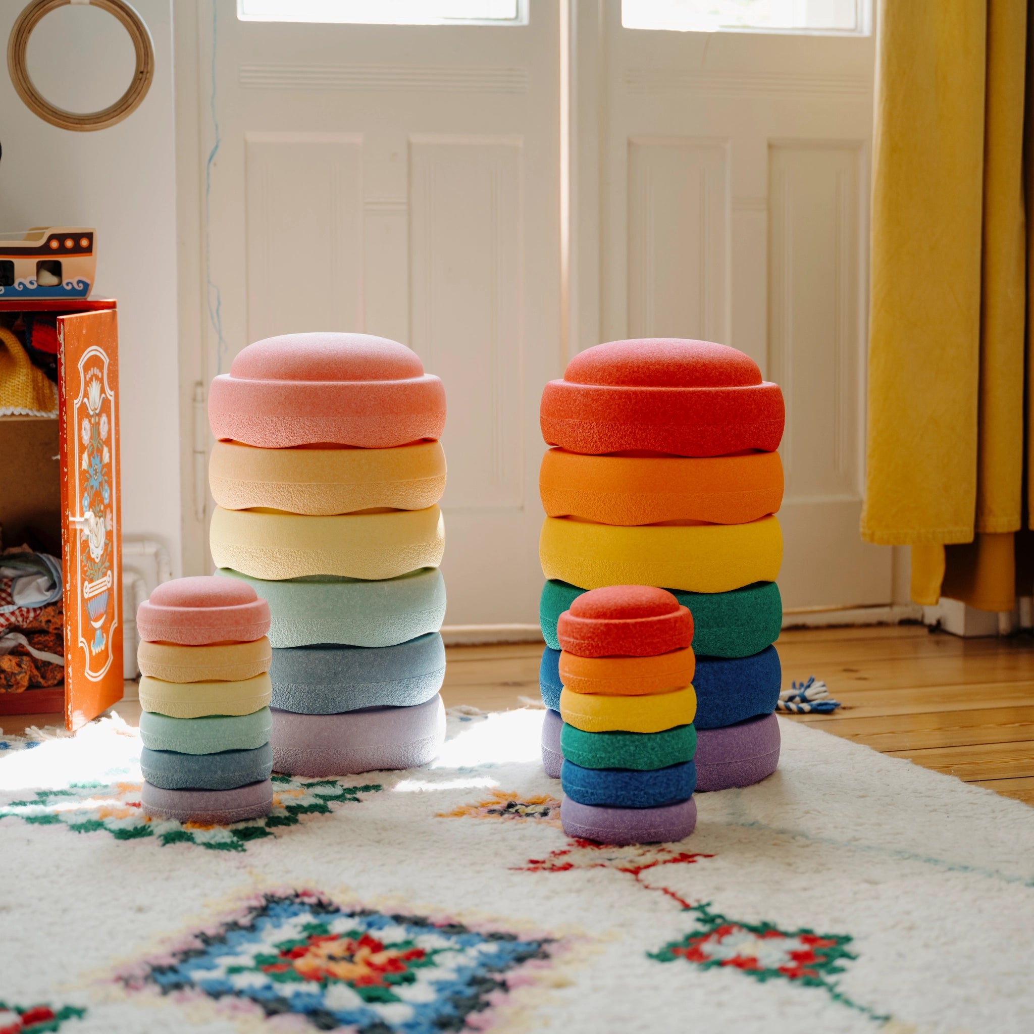 Stapelstein: Mini Regenbogen Classic (6 Steine) im hellen Spielzimmer, präsentiert als bunte, weiche Stapeltürme auf weißem Teppich. Perfekt für nachhaltiges, ästhetisches Spielvergnügen, ideal für moderne, umweltbewusste Familien.