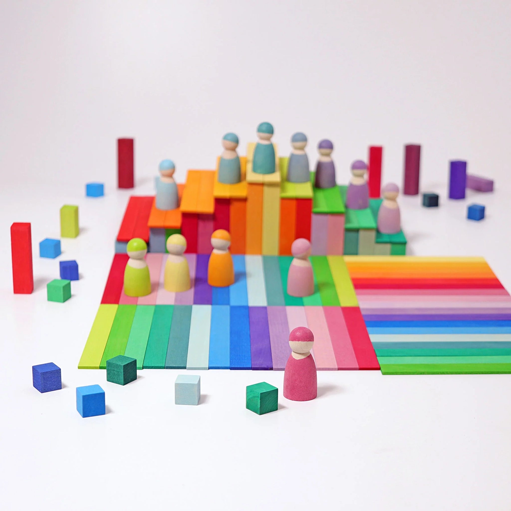 Freies Spiel: Kleine Stufenpyramide – Ein Arrangement aus bunten, rechteckigen Holzplättchen, Holzfiguren und Würfeln für kreatives Spielen. Hergestellt aus lasiertem Lindenholz, fördert es Feinmotorik und Kreativität.