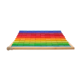 Freies Spiel: Große Stufenzählstäbe, ein Set aus 100 farblich lasierten Bauklötzen in einem Holzrahmen, fördert räumliches Denken und Mathematik. Ein kleines Schneckenhaus liegt im linken unteren Eck.