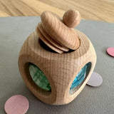 Mehrere kleine Holzdosen und Bauspiel-Elemente in Pastellfarben.