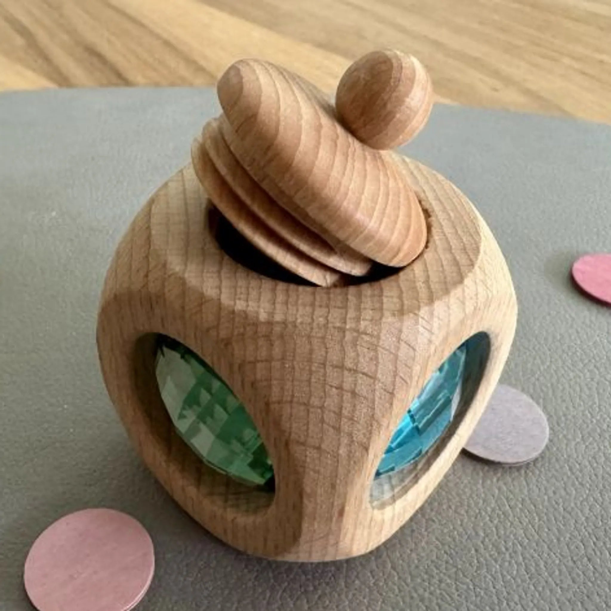 Mehrere kleine Holzdosen und Bauspiel-Elemente in Pastellfarben.