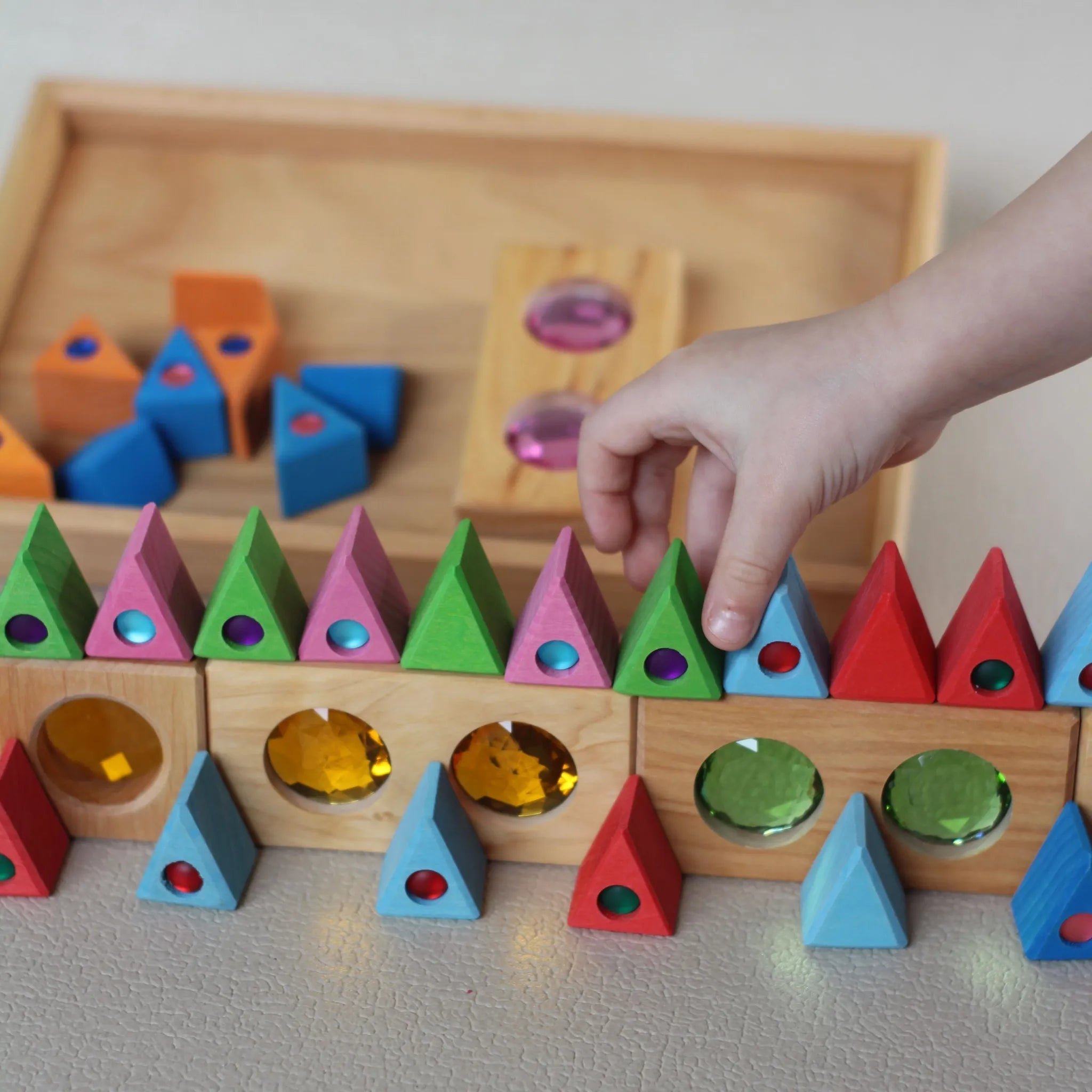Kleine Bauspiel-Teile in den Fächern einer Holz-Sammlerbox.